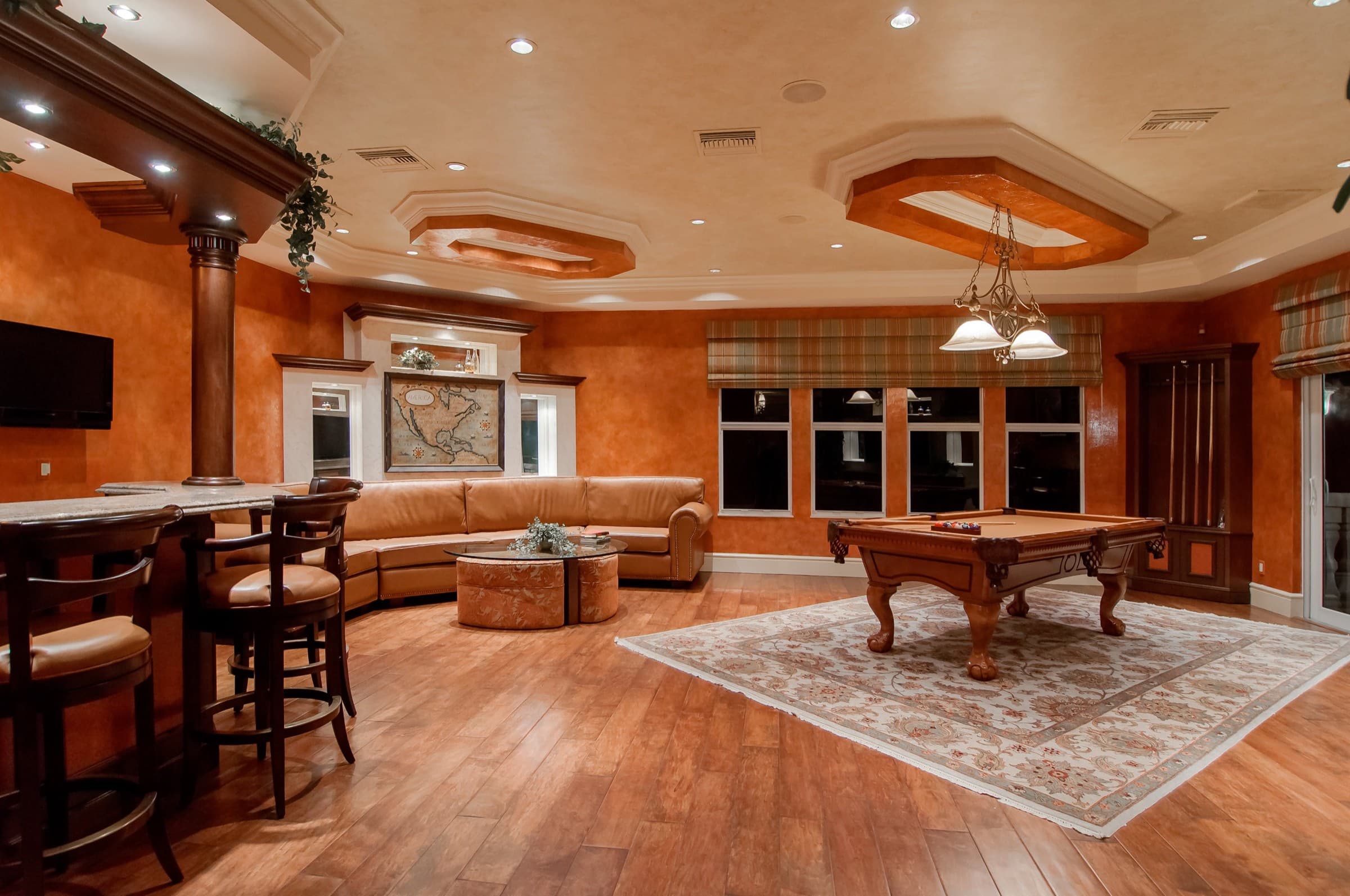 A finished lower-level rec room with a pool table and a sectional sofa.