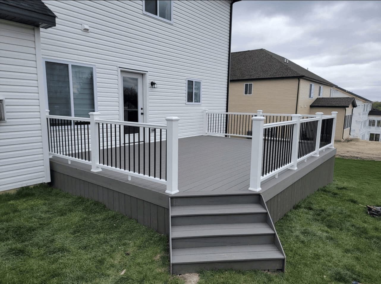 A composite deck with white railings and stairs, built by Anchor & Beam